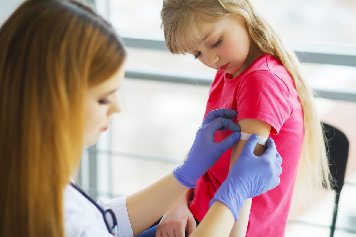 Doctor injecting flu vaccination in little girl's arm