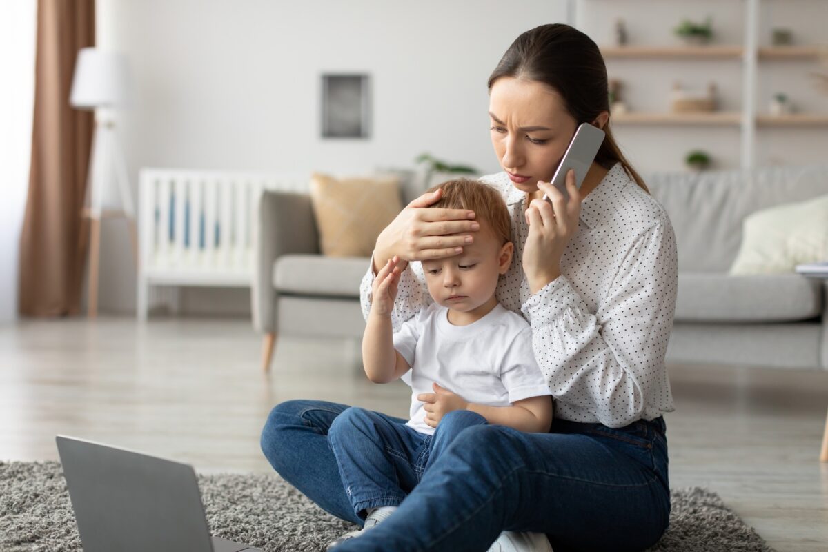 Stressed mother talking on phone to doctor, worried about her son's fever